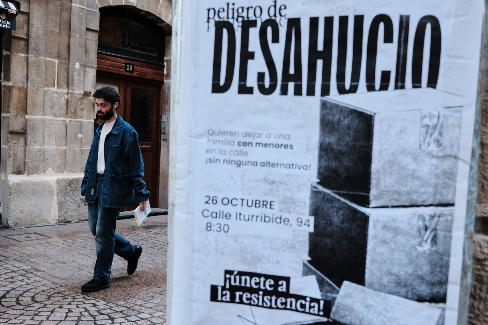 Transeúnte caminando junto a un gran cartel informativo en las calles de Bilbao.
