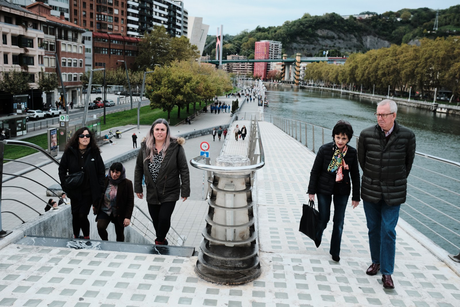 Grupo de personas caminando ordenadamente por el paseo fluvial de Bilbao.
