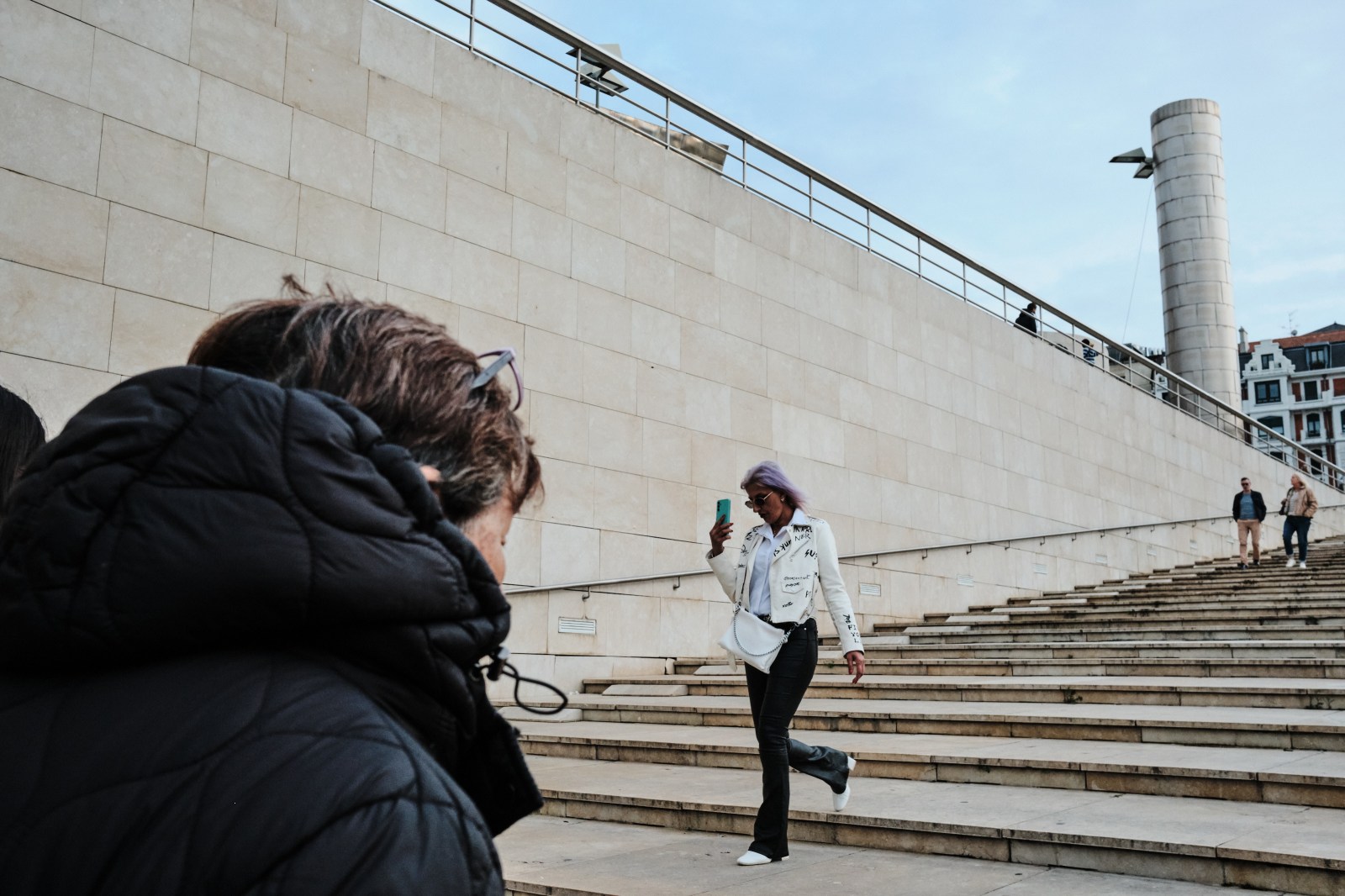 Personas bajando las escaleras exteriores de un edificio emblemático en Bilbao.