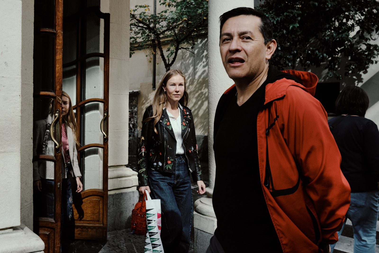 Taller de Inmersión en Fotografía de Calle en Madrid con Rober Tomás, señor de rojo y detrás unas chicas rubias saliendo de una cafetería