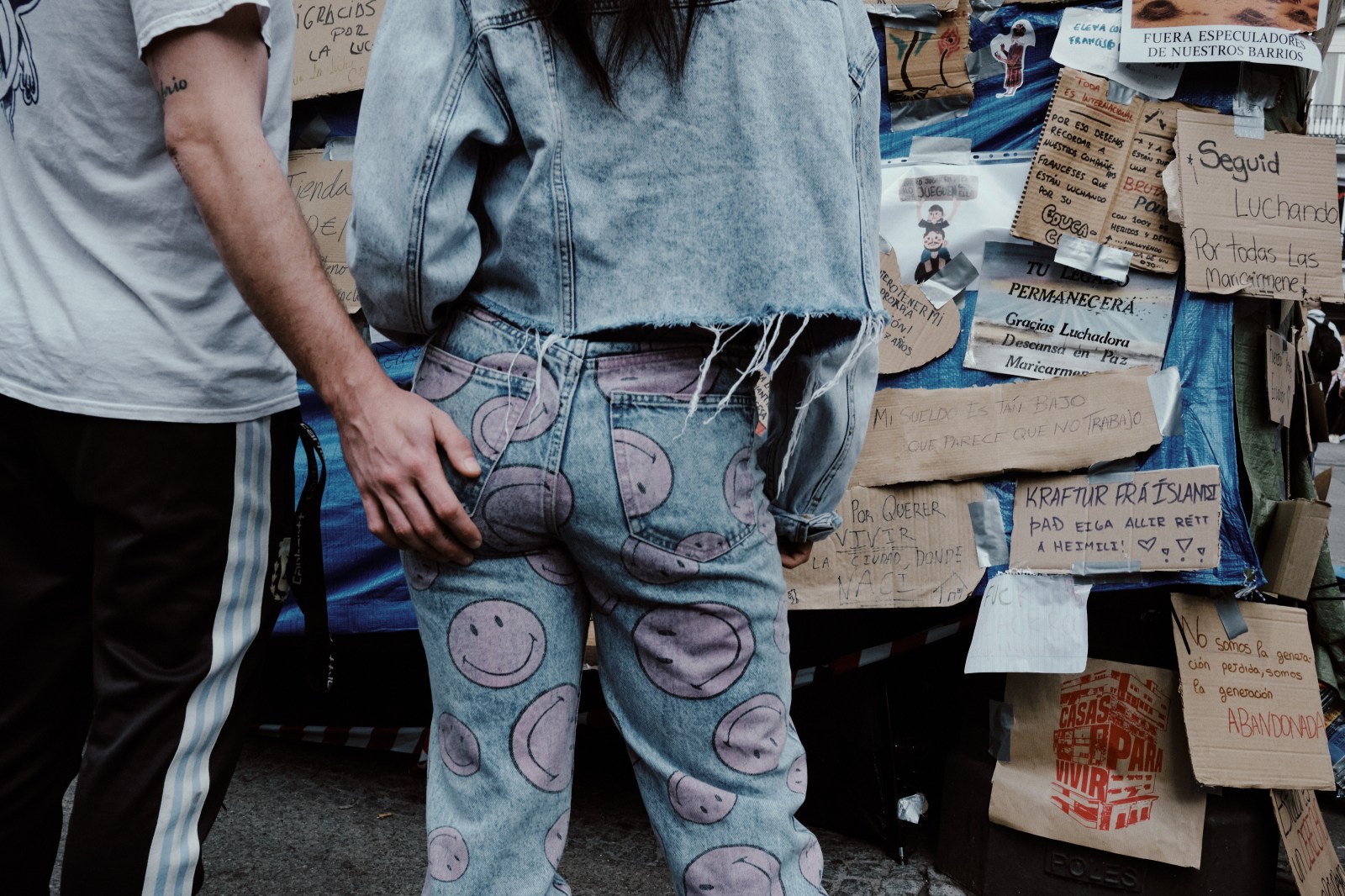 Taller de Inmersión en Fotografía de Calle en Madrid con Rober Tomás. Manifestación en Puerta del Sol, pareja joven leyendo los carteles de protesta
