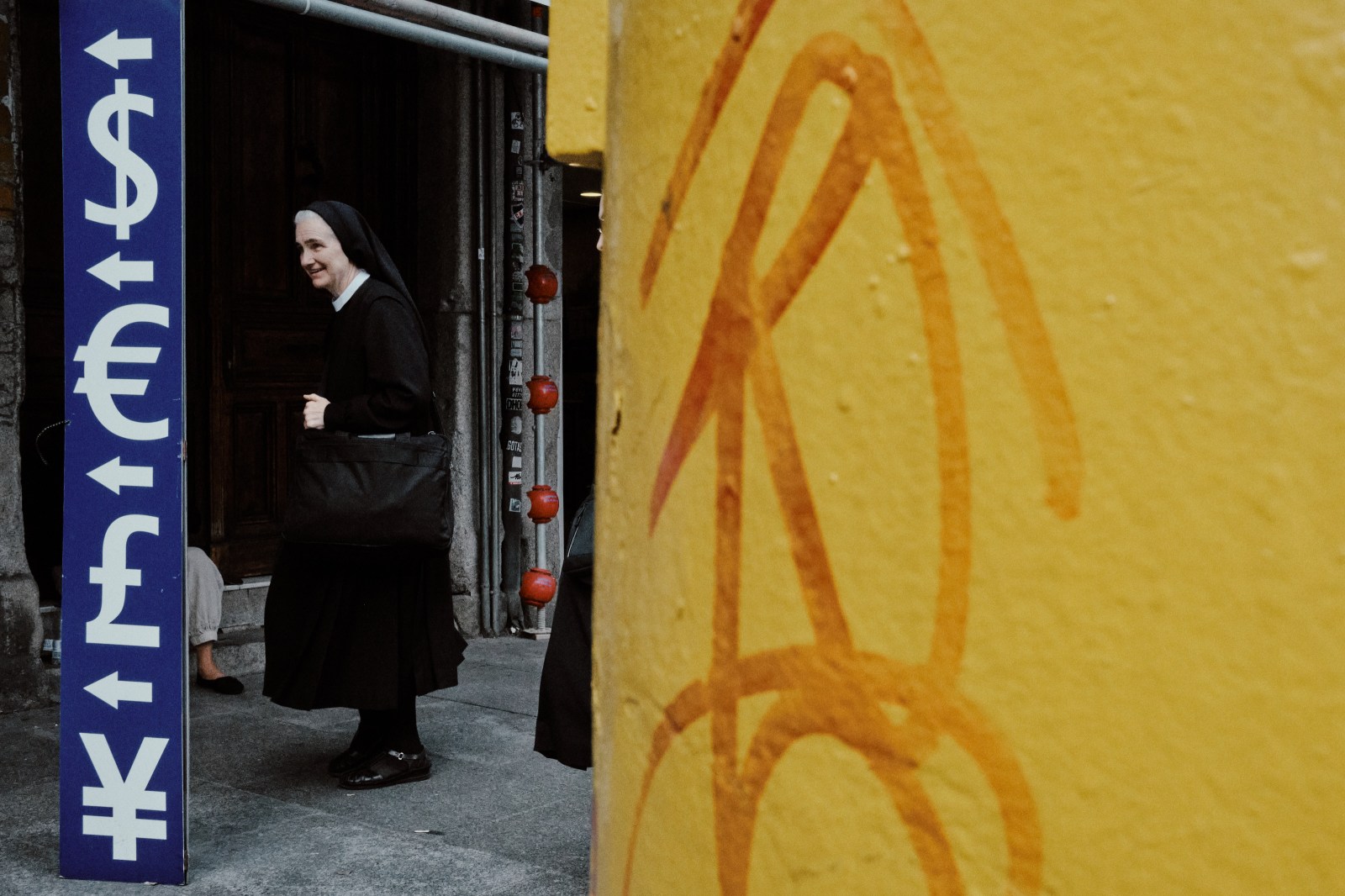 Taller de Inmersión en Fotografía de Calle en Madrid con Rober Tomás. Una monja pasa delante de una casa de cambio de dinero