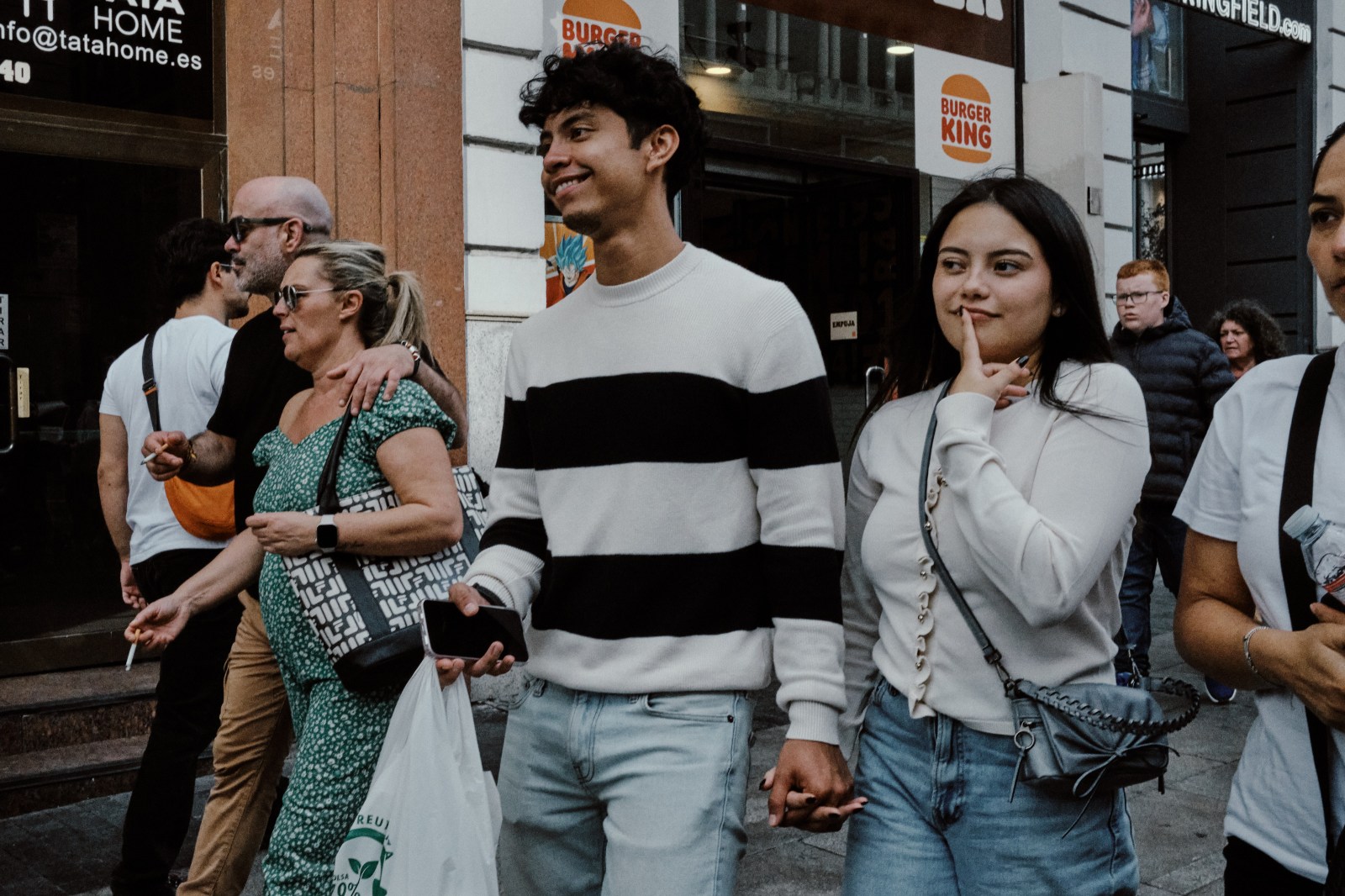 Taller de Inmersión en Fotografía de Calle en Madrid con Rober Tomás. Personas pasando por la Gran Vía mientras una chica se pone el dedo en los labios