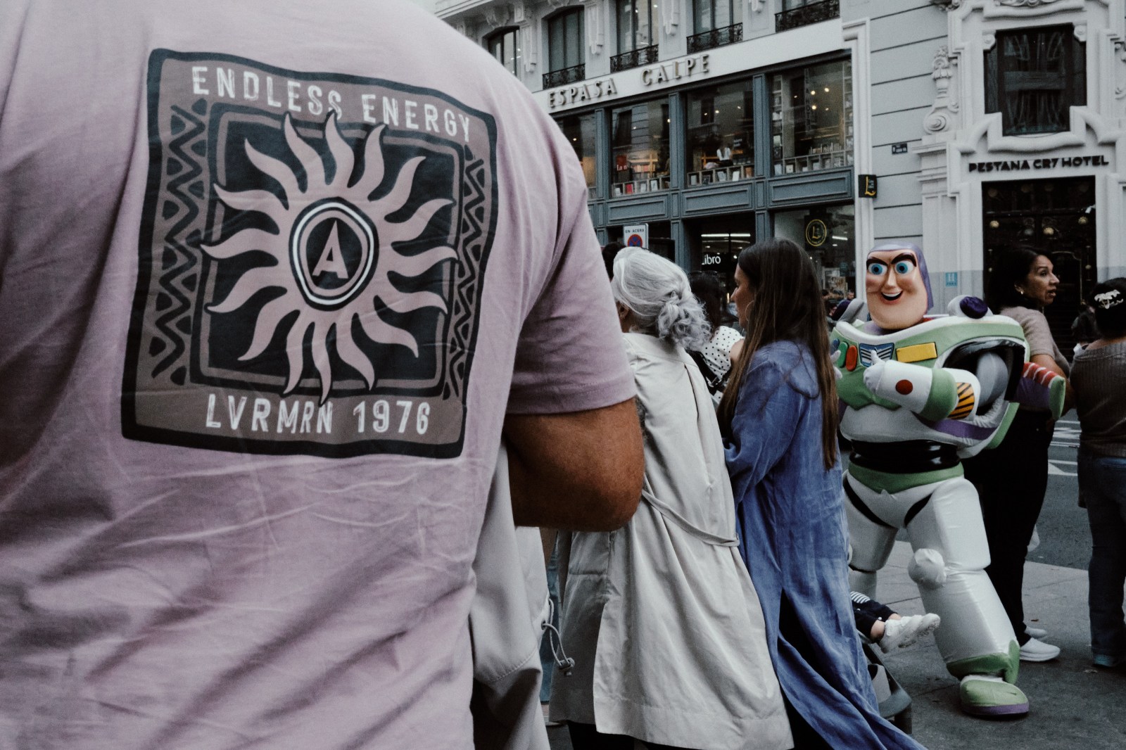 Taller de Inmersión en Fotografía de Calle en Madrid con Rober Tomás. Una camiseta rosa con frases de energía y un muñeco de Buzzlight year de Pixar Toy Story en Gran Vía