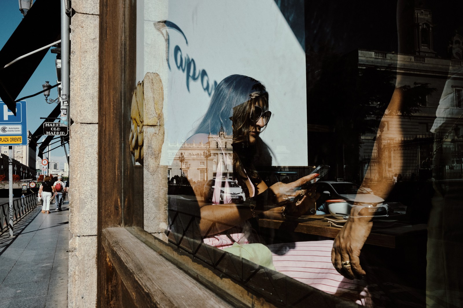 Taller de Inmersión en Fotografía de Calle en Madrid con Rober Tomás. Mujer rubia mirando el movil mientras espera la comida en un restaurante