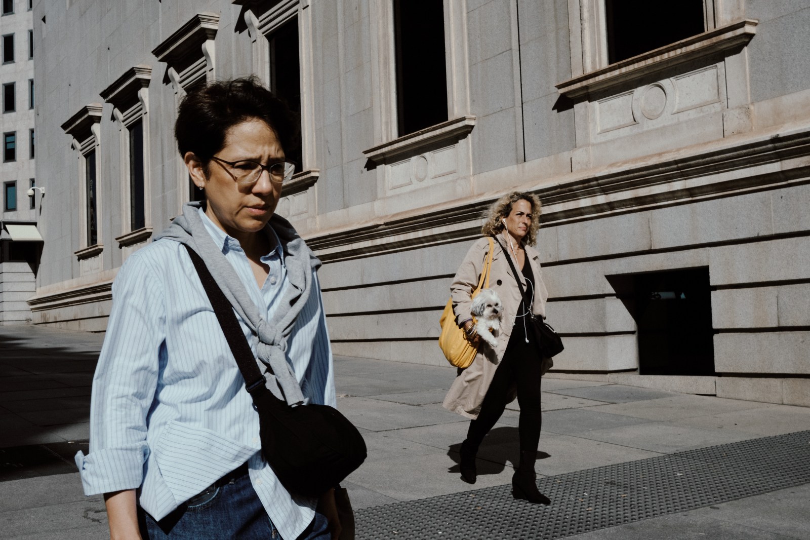 Taller de Inmersión en Fotografía de Calle en Madrid con Rober Tomás, dos señoras caminando por la Cuesta de los Jerónimos y una de ellas lleva un perro pequeño en brazos 