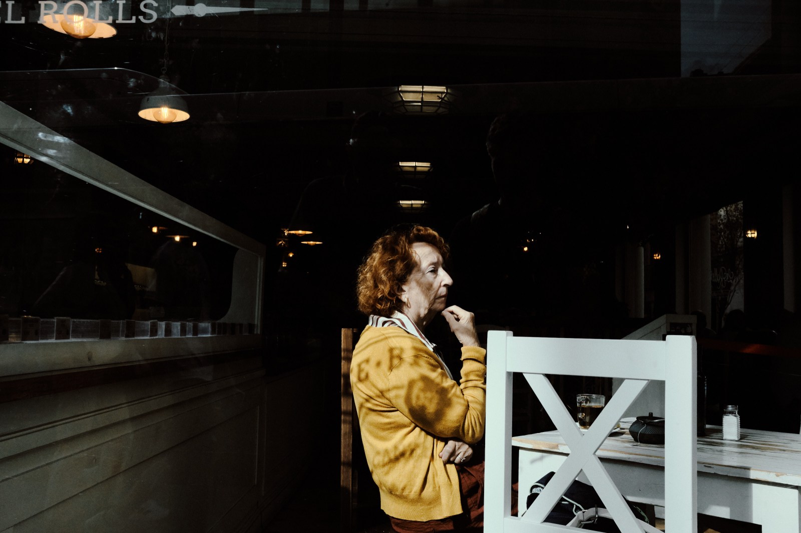 Taller de Inmersión en Fotografía de Calle en Madrid con Rober Tomás. Señor pensativa de amarillo en una cafetería con bonita luz en la ventana